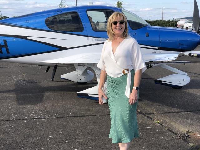 Lisa Marie Boyd standing in front of the Boyds' blue-and-white Cirrus airplane