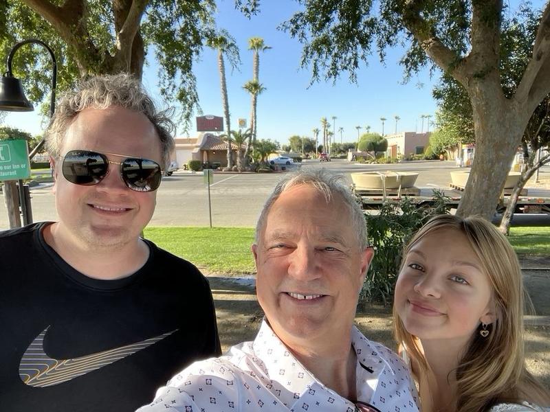Sunny selfie of Mark Boyd with his oldest granddaughter, Olivia, and a family member, palm trees behind them