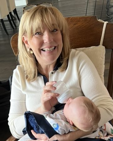 Lisa Marie Boyd in a wooden rocking chair, bottle-feeding a baby grandchild